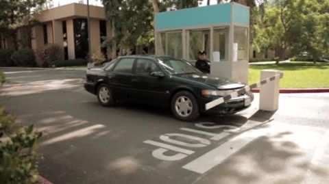 1993 Ford Taurus - A dark green sedan is stopped at a security booth with a barrier arm. The car appears to be a 1992 model.