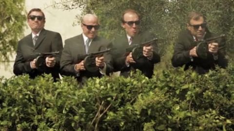 1993 Ford Taurus - Four men in suits, armed with tommy guns, are positioned behind a hedge, ready for action.