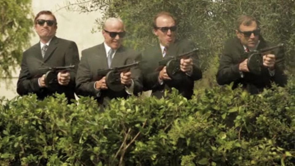 Four men in suits with tommy guns emerge from bushes