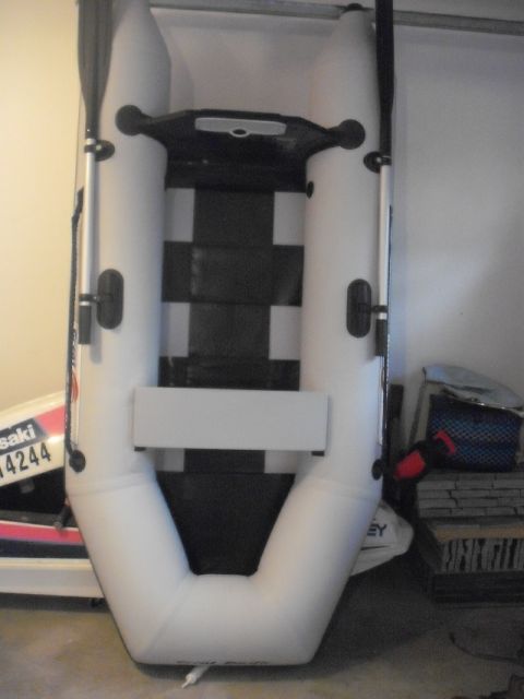 1990 Ford Bronco - An inflatable boat with black seating and oars is shown, with a partial view of another watercraft in the background.