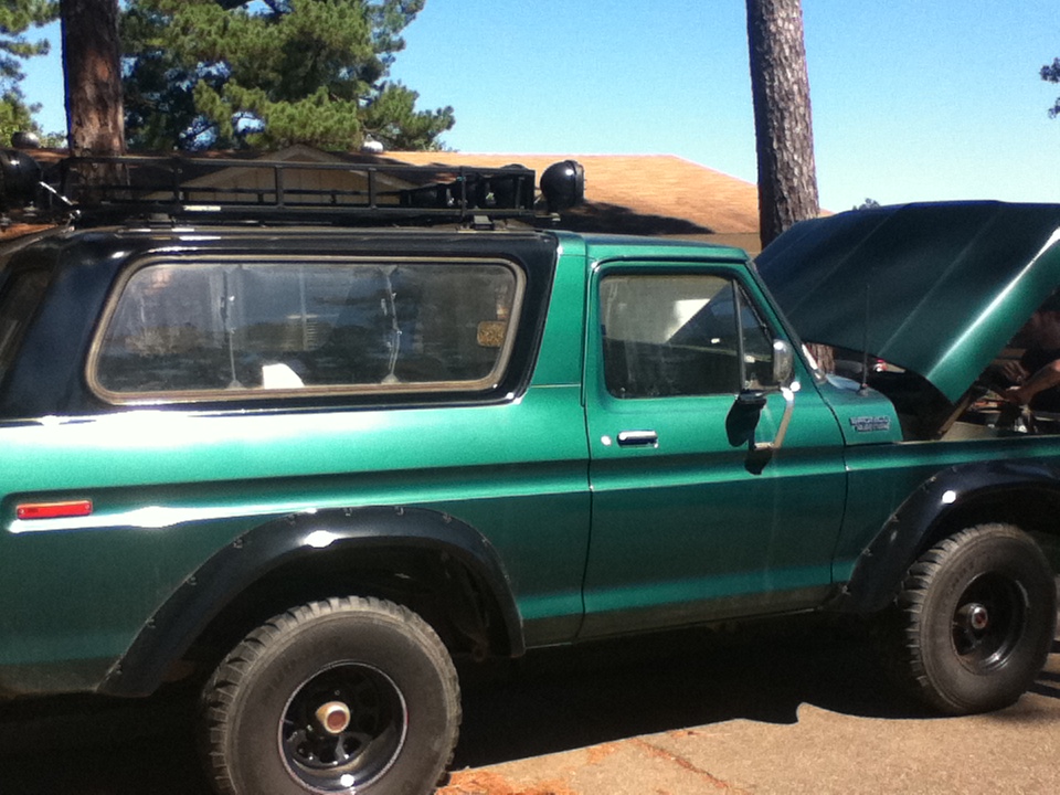 Green 1978 Ford Bronco with roof rack, hood open