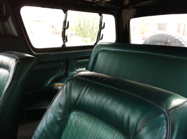 1978 Ford Bronco interior showing green vinyl seats and rear tire mounted on the back door