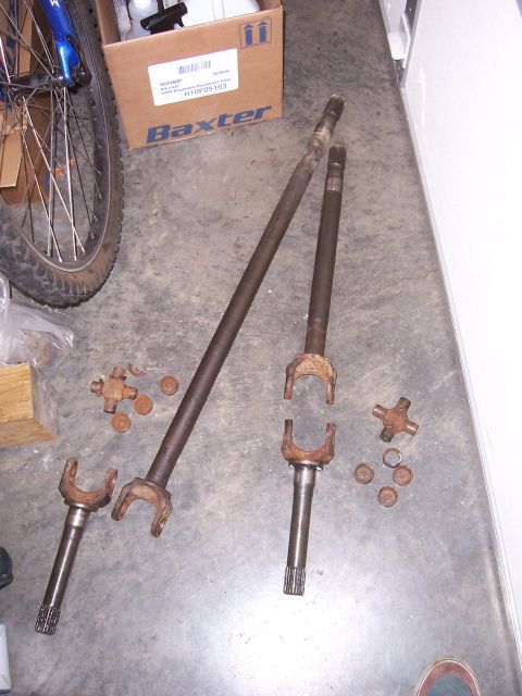 1992 Ford Bronco - Drive shafts and U-joint parts are laid out on a garage floor.