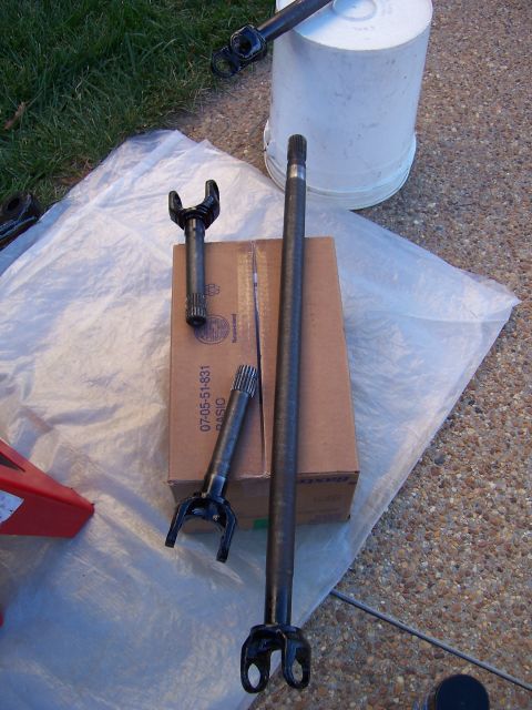 1992 Ford Bronco - Several axle shafts are displayed on a tarp, with a cardboard box and a white bucket in the background.