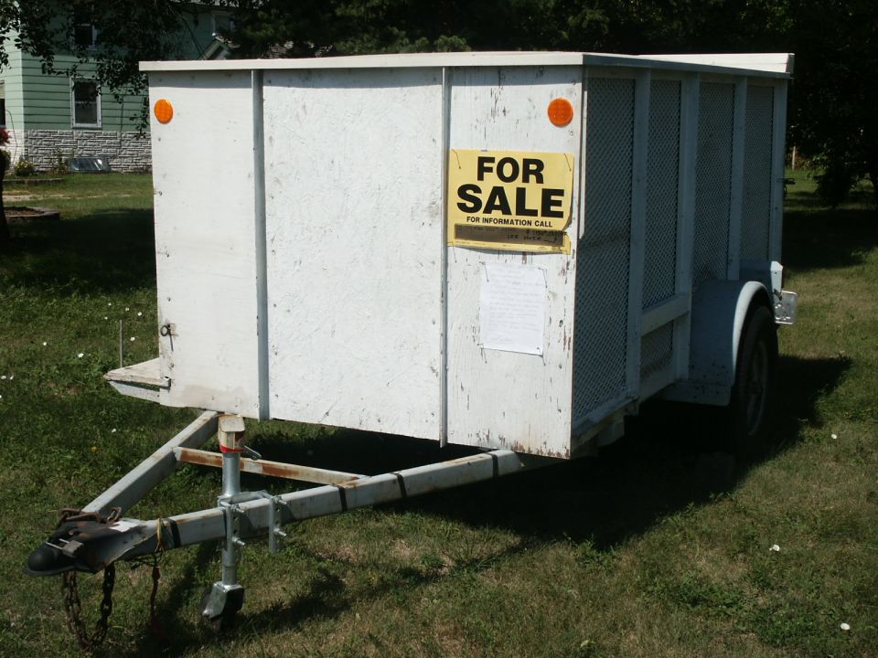White utility trailer with a 'For Sale' sign on the side
