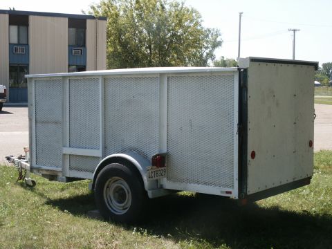 1990 Ford Bronco - A white utility trailer is parked on a grassy area next to a building.