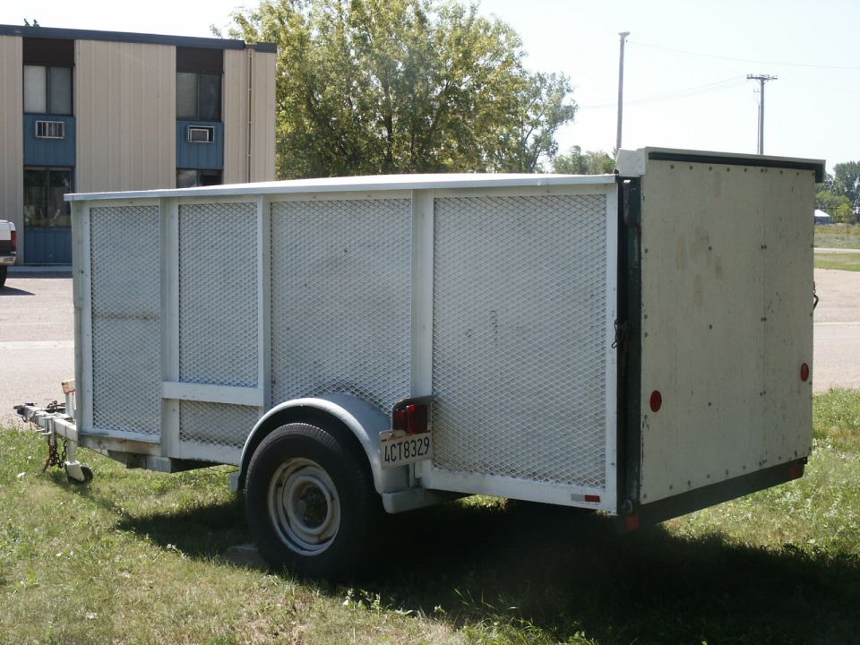 White utility trailer with diamond plate sides and a closed rear door. License plate reads 4CT8329