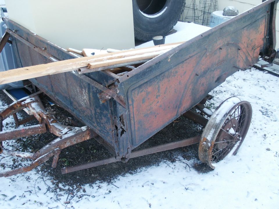 Rusted trailer bed with wooden planks and a spoked wheel