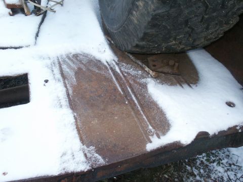1990 Ford Bronco - A close-up view of a trailer frame and tire, partially covered in snow.