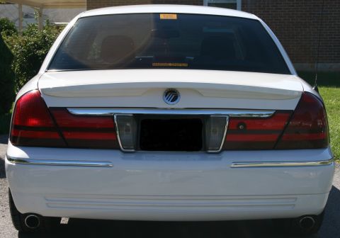 2005 Mercury Grand Marquis - Rear view of a white sedan with horizontal taillights and chrome accents, showing a spoiler and a watermark.