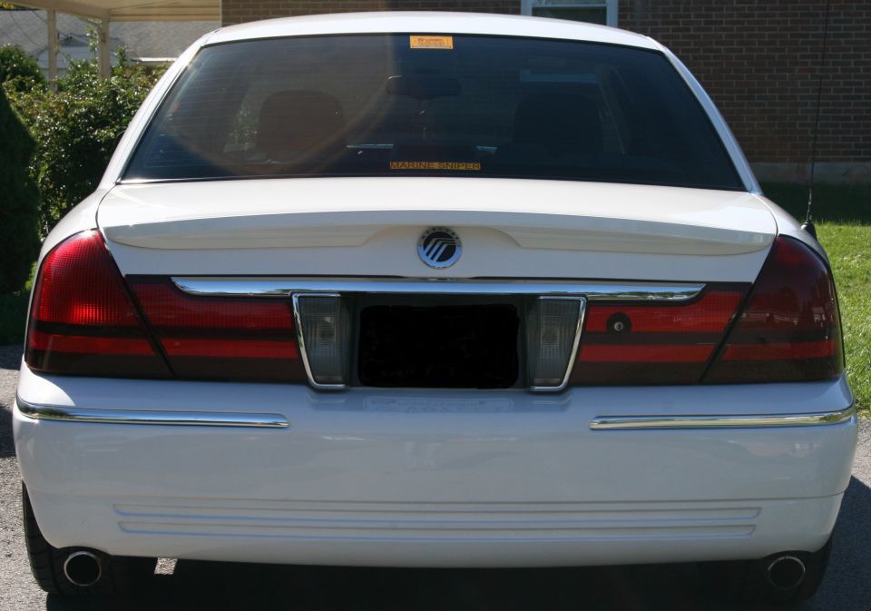 White sedan rear view, chrome trim, horizontal taillights, spoiler, and a SuperMotors watermark