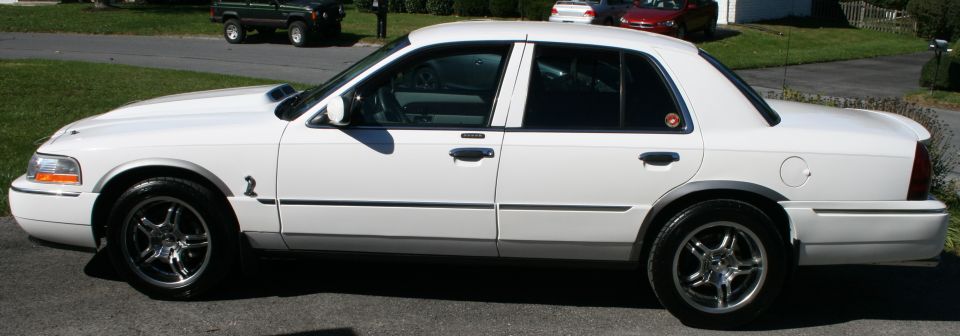 White sedan side view with aftermarket wheels and hood scoop