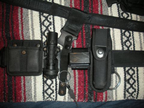 1996 Ford Bronco - A tactical belt holds a flashlight, spare magazine, and other gear, resting on a patterned blanket.