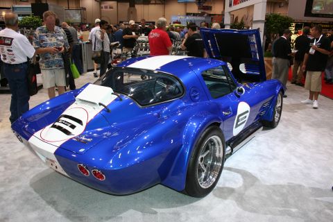 1998 Ford Crown Victoria - Rear three-quarter view of a blue and white vintage-style Corvette Grand Sport coupe with number graphics on an indoor display.