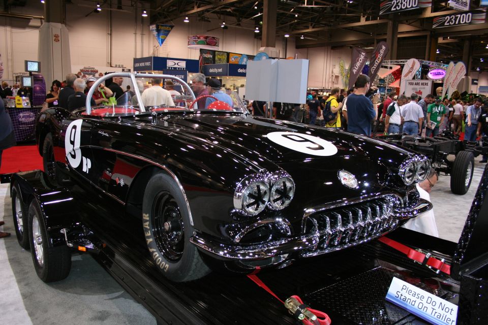 Black vintage Corvette race car number 9 on a trailer indoors
