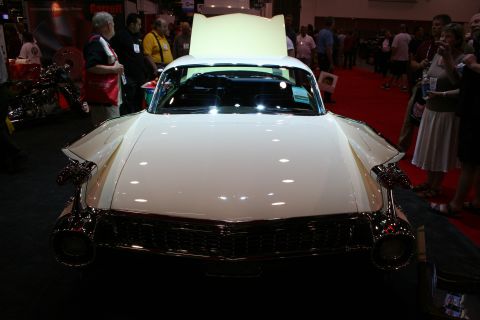 1998 Ford Crown Victoria - Head-on view of a cream vintage Cadillac showing its broad chrome grille, bullet bumper guards and raised hood at an indoor show.