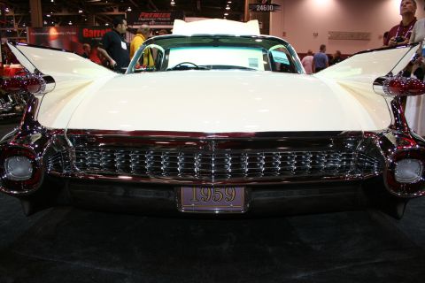 1998 Ford Crown Victoria - Front of a white 1959 Cadillac with sweeping tailfins, chrome grille and a license plate reading 1959 on display indoors.