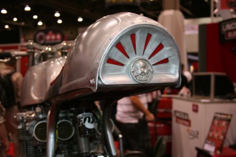 1998 Ford Crown Victoria - Detail of a bare-metal custom motorcycle tail section with a red sunburst cutout and a round rider emblem medallion.