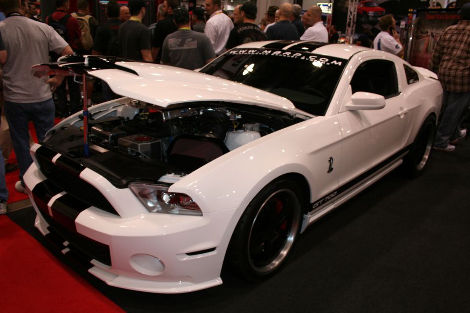 White Shelby GT500 Mustang with black stripes and open hood at show