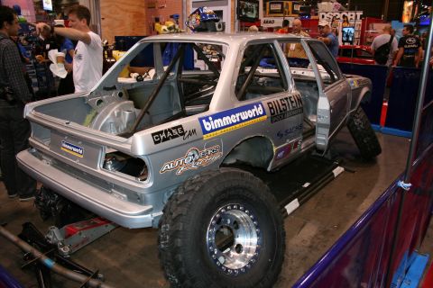 1998 Ford Crown Victoria - bare-metal off-road race truck under construction with a full roll cage, beadlock wheels and sponsor decals like Bilstein and Bimmerworld.
