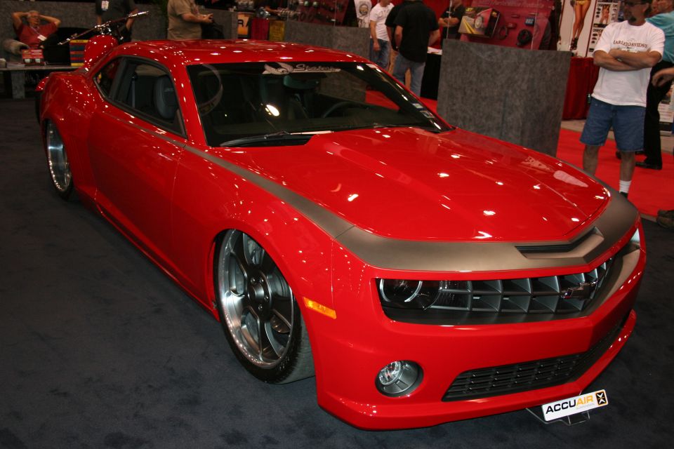 Red Chevrolet Camaro with matte hood stripe and polished wheels at show