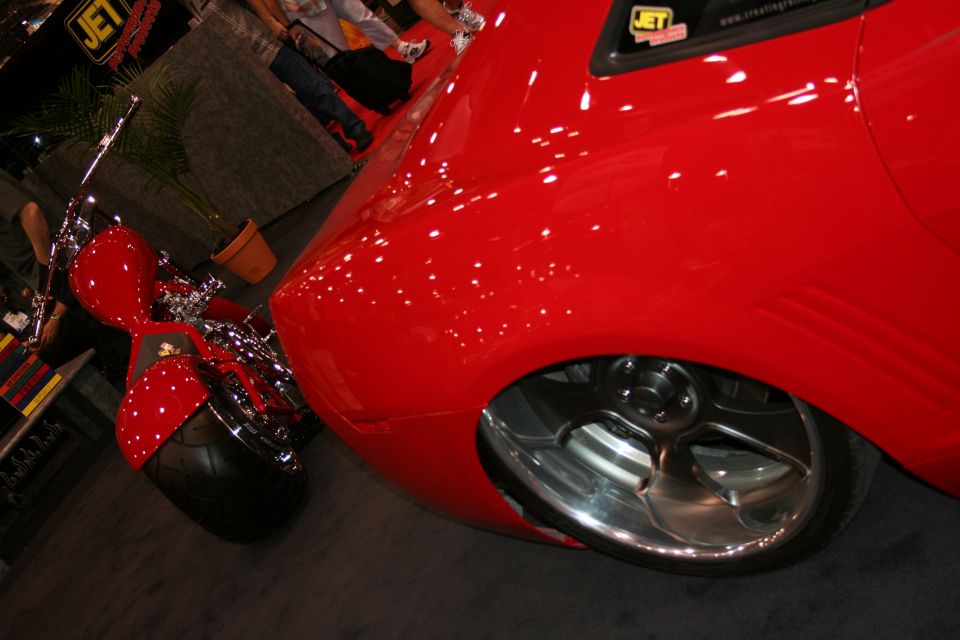 Close-up of red sports car front fender, wheel and chrome accessory