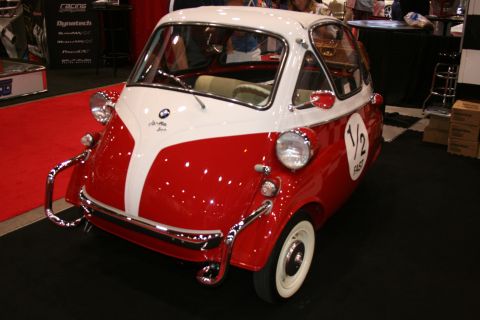 1998 Ford Crown Victoria - red-and-white BMW Isetta microcar with its front-opening door, displayed on a red carpet at an indoor show.