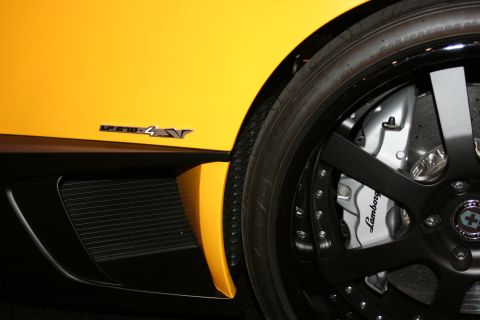 1998 Ford Crown Victoria - Close-up of a yellow Lamborghini LP-series fender badge beside a black wheel with a Lamborghini-branded brake caliper.