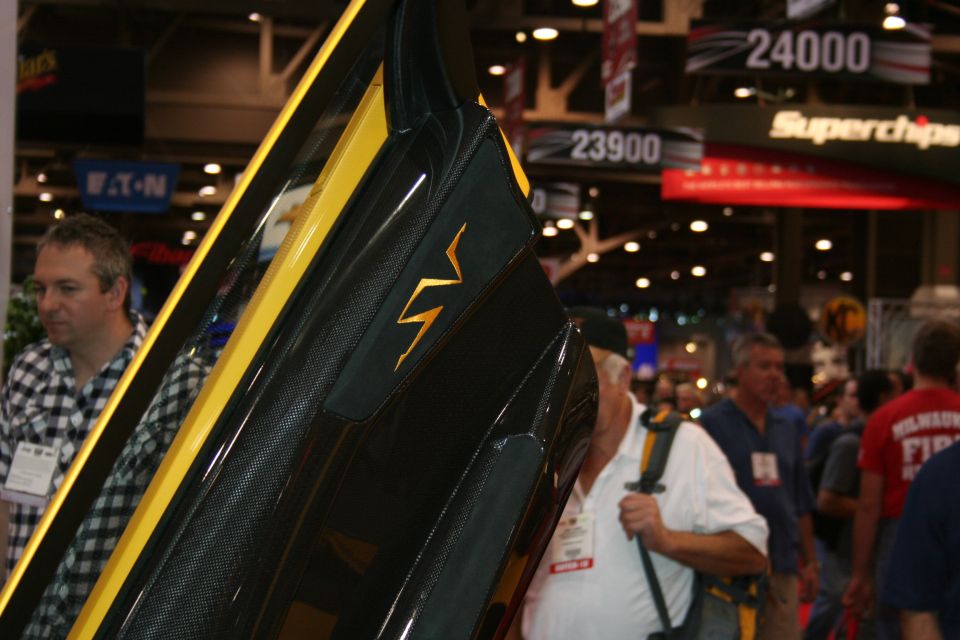 Close-up of a black carbon-fiber door with a yellow lightning-bolt SV emblem