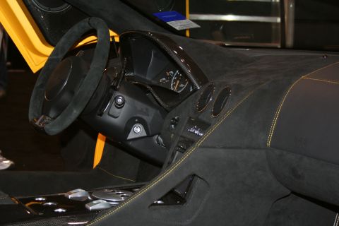 1998 Ford Crown Victoria - Close-up of a supercar cockpit with a flat-bottom suede steering wheel, gauge cluster and black dash trimmed in yellow stitching.