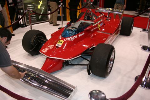 1998 Ford Crown Victoria - red vintage Ferrari Formula 1 single-seater with slick tires displayed behind rope barriers as a man photographs it.