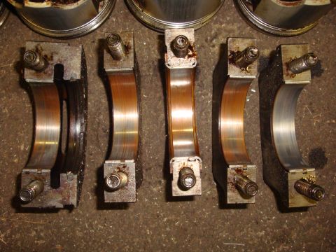 1989 Ford Bronco - Engine crankshaft bearings are shown, some with visible wear, on a workshop floor.