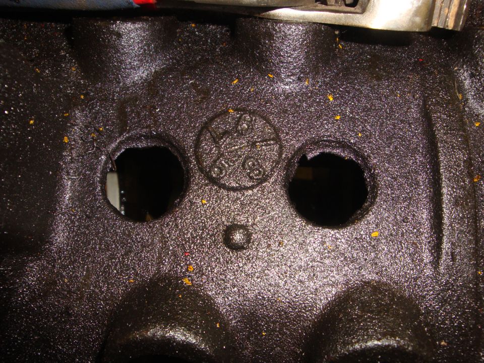Engine block casting with circular stamp showing numbers and symbols, two circular openings, and a small raised bump
