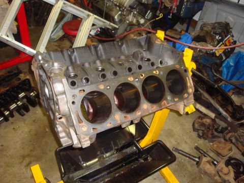 1989 Ford Bronco - Engine block on a stand in a workshop setting, with a crankshaft nearby.