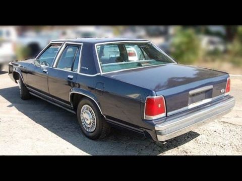 1991 Ford Crown Victoria - A dark blue sedan with chrome accents and a vinyl roof is parked outdoors.