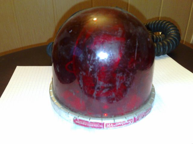 Red emergency light with a silver base and a black hose attached