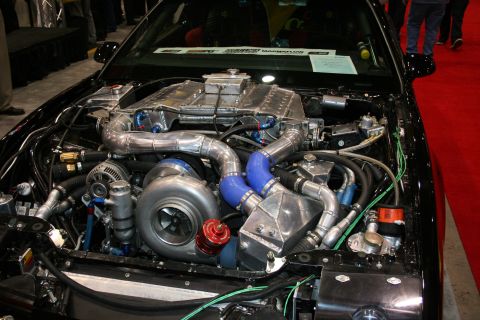 1998 Ford Crown Victoria - Detailed engine-bay view of a built motor featuring a large turbocharger, polished intercooler piping and blue silicone hoses.