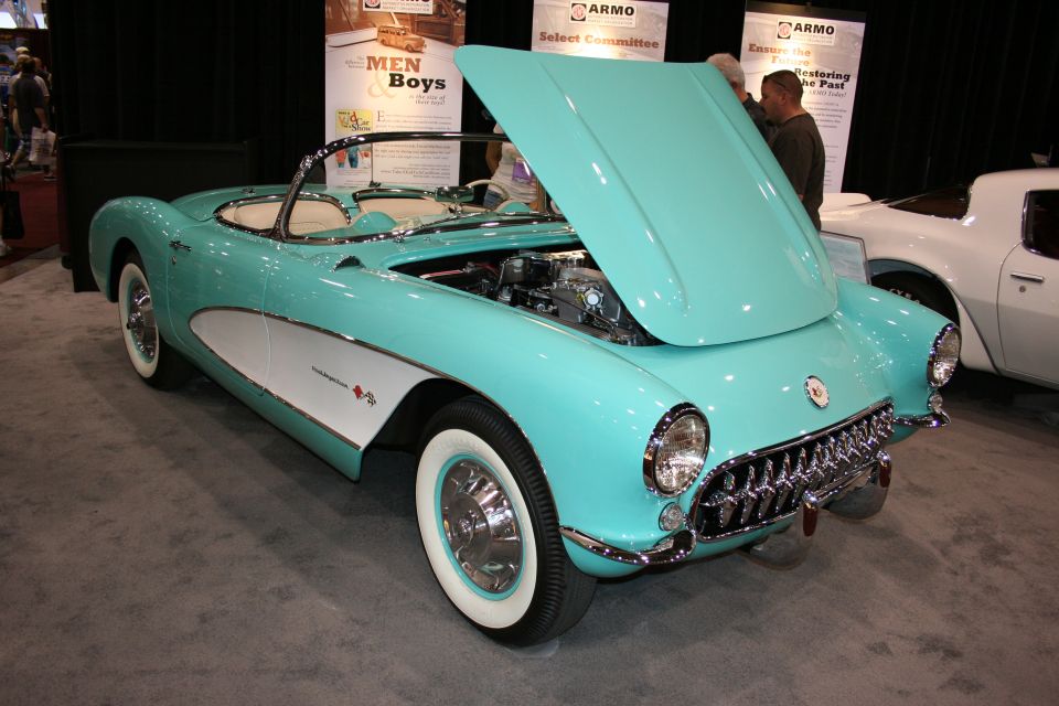 Turquoise 1950s Chevrolet Corvette convertible with open hood at a show
