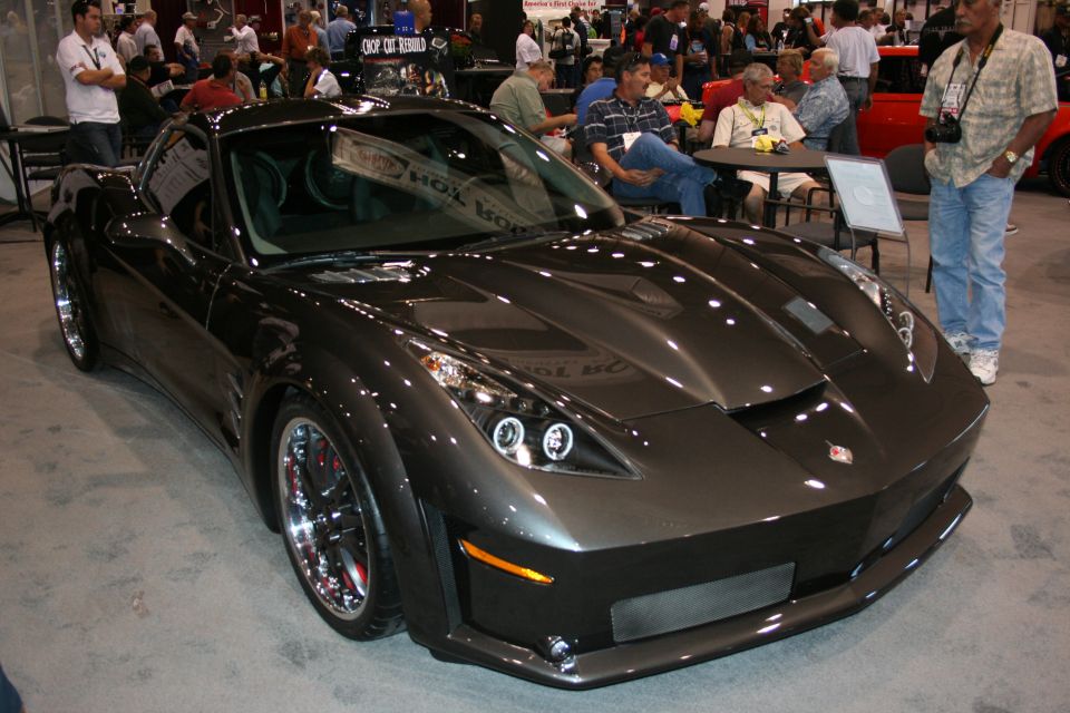 Dark gray custom Corvette-style coupe with wide body and chrome wheels