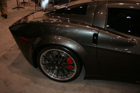 1998 Ford Crown Victoria - Rear-quarter detail of a gray custom coupe showing its flared fender, multi-spoke chrome wheel and red brake caliper.