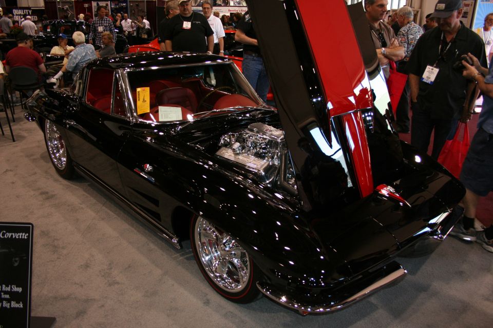 Black Corvette coupe with open hood and red interior at car show