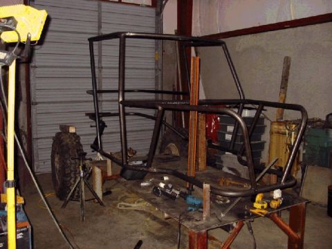 1994 Ford Bronco - Custom roll cage frame being built in a workshop, spare tire is mounted to the side.
