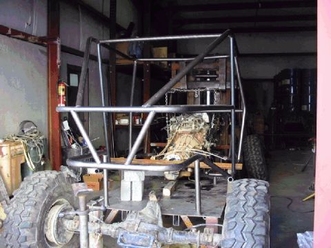 1994 Ford Bronco - This vehicle is undergoing modifications in a workshop, with its engine exposed and a custom roll cage being installed.