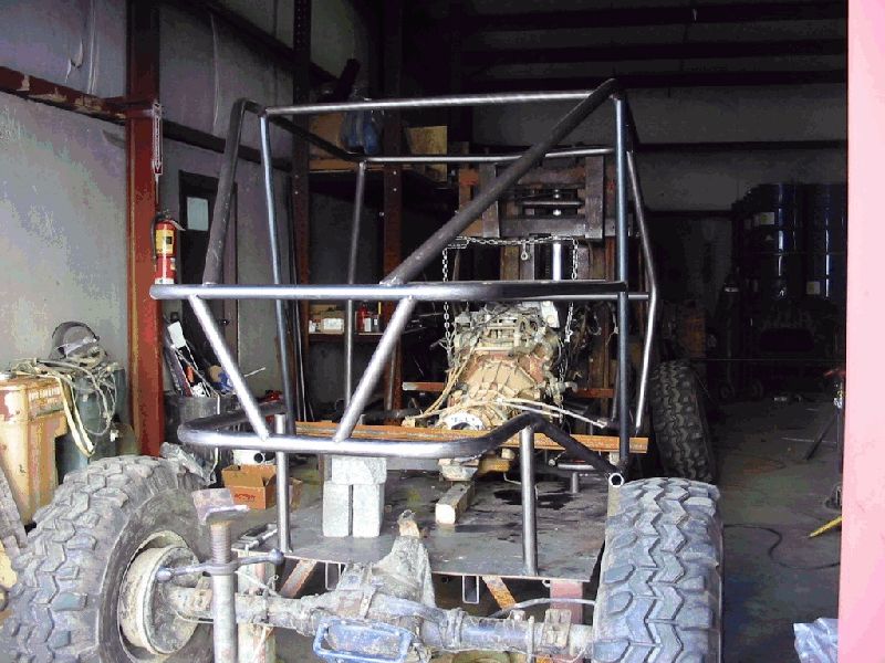 Bare tube-chassis off-road buggy with welded roll cage under construction in a shop