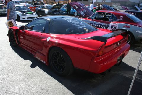 1998 Ford Crown Victoria - red Honda NSX track car with a rear wing and sponsor decals sits among other show cars in an outdoor lot.