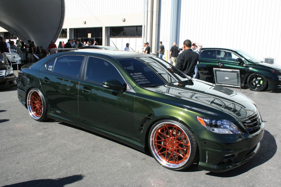Lowered dark green luxury sedan on copper-colored wheels indoors