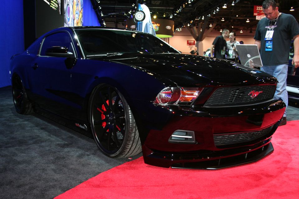 Black Mustang coupe front three-quarter on red carpet at a show