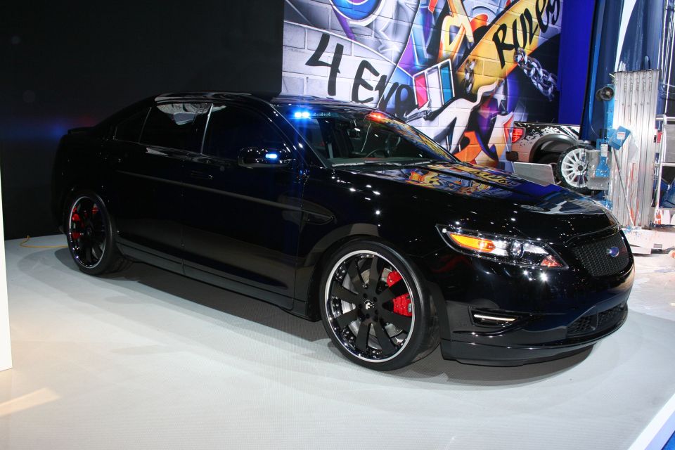 Black Ford Taurus sedan front three-quarter on white show stage