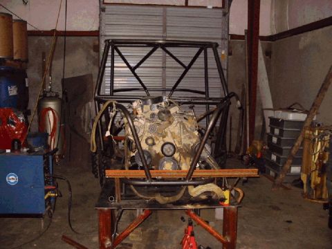1994 Ford Bronco - Engine and roll cage assembly in a workshop setting, with welding equipment nearby.