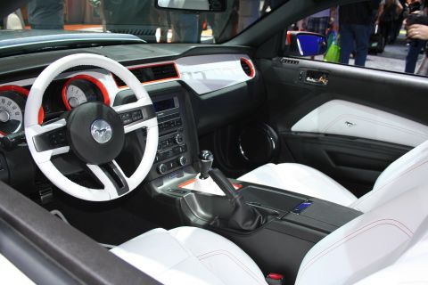 1998 Ford Crown Victoria - Interior of a Ford Mustang showing a white steering wheel and white leather seats with red and orange accents.